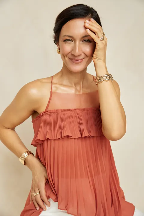 Kati Martin – Porträt im rostroten Kleid mit Hand am Kopf