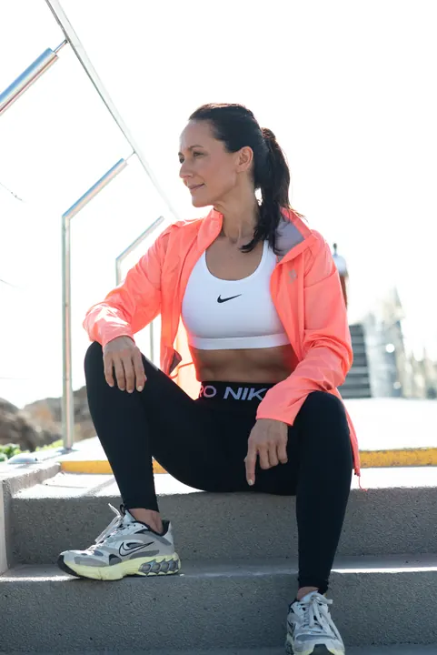 Kati Martin – Sport-Aufnahme mit korallfarbener Jacke auf einer Treppe